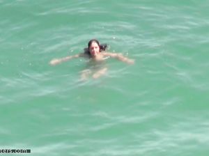 Парень издали подглядывает за девушкой, которая голышом плавает в море